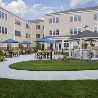 A well-maintained courtyard in an apartment complex featuring a gazebo and outdoor seating with blue umbrellas.