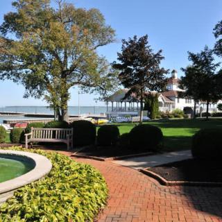 A scenic garden view with a bench, gazebo, and lake in the background.