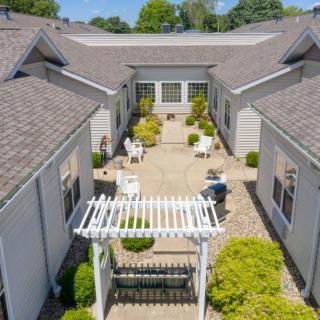 A serene residential courtyard featuring a white pergola and well-maintained garden landscaping.