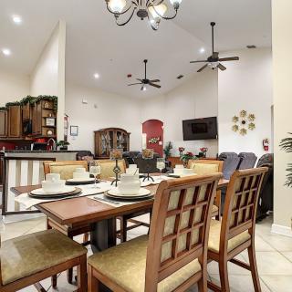 A modern and spacious dining room with a well-set table, adjacent to an open kitchen area.