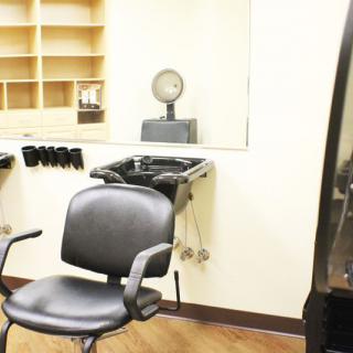 An interior view of an empty hair salon station with a chair and washing sink.
