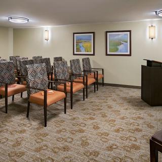 A small conference room with neatly arranged chairs facing a podium.