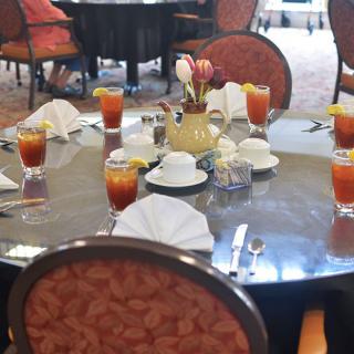 A round dining table set with glasses of iced tea and arranged tableware in a restaurant setting.