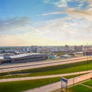 A panoramic view of a city skyline with roads and modern buildings under a vibrant sky.