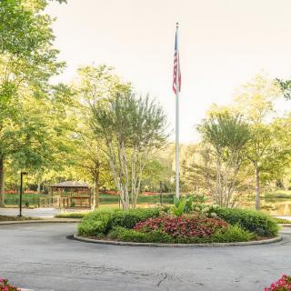 A serene park with a central flagpole surrounded by trees and well-maintained landscaping.