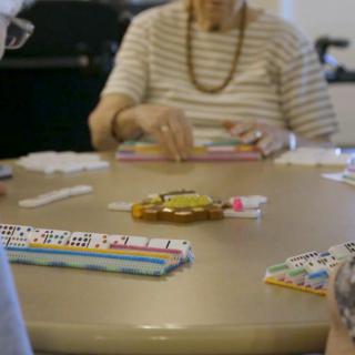 A group of people playing Mahjong at a table.