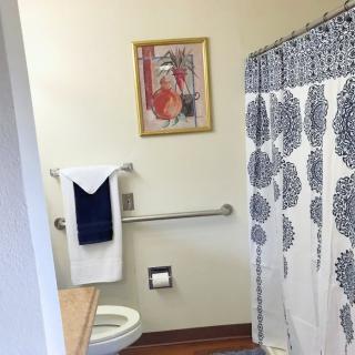 A bathroom with a decorative shower curtain, wall art, and neatly arranged towels.