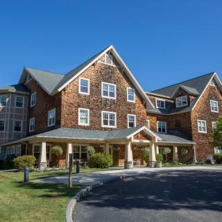 A modern residential building with a gabled roof and stone facade under a clear blue sky.