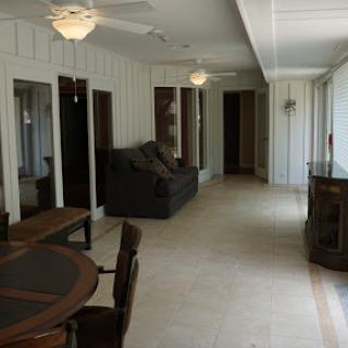 A spacious living area featuring a comfortable sofa and a dining table, illuminated by ceiling fans.