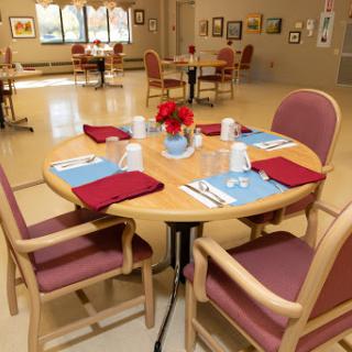 A well-prepared dining area with a round table set for guests, featuring decorative elements and an inviting atmosphere.