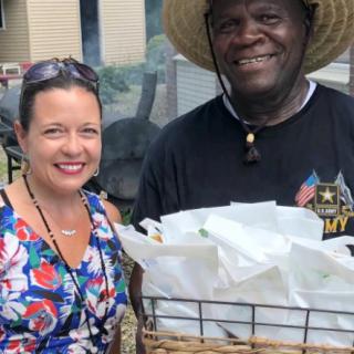 Two people smiling outdoors, one holding a basket.