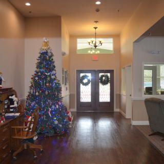 A warmly decorated living room with a Christmas tree and wreaths on the doors.
