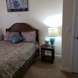A cozy bedroom with a bed, nightstand, and a lamp.