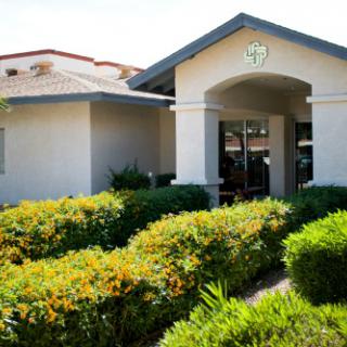 A welcoming entrance to a well-maintained building surrounded by lush greenery.