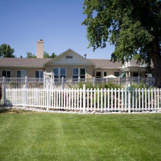 A suburban house with a white picket fence and a well-maintained lawn.