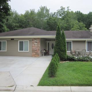 A one-story suburban house with a well-maintained lawn and trees.