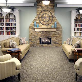 A cozy living room with a stone fireplace, surrounded by bookshelves and comfortable sofas.
