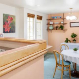A cozy dining room with a round table and chairs, adorned with plants and artwork.