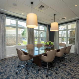 A modern conference room with a large table, chairs, and pendant lighting.