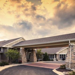 A residential building with a covered entrance under a dramatic sunset sky.