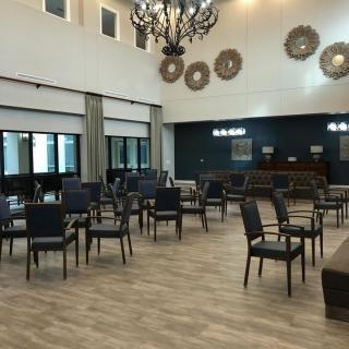 A spacious meeting room with a chandelier, chairs arranged in rows, and decorative wall accents.