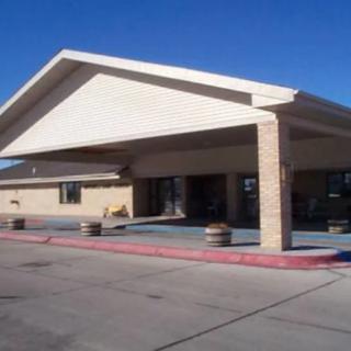 The image shows the entrance of a motel with a covered driveway and parking area.