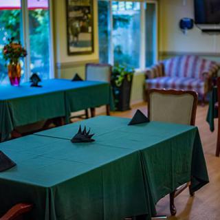 A cozy restaurant dining area with tables covered in green tablecloths, neatly folded napkins, and comfortable seating.