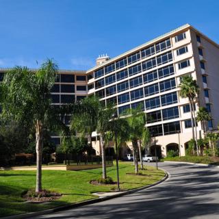 A modern hotel surrounded by palm trees and well-maintained landscaping on a sunny day.
