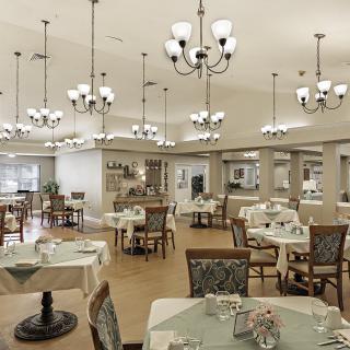 An elegant dining room with chandeliers and neatly arranged tables and chairs.