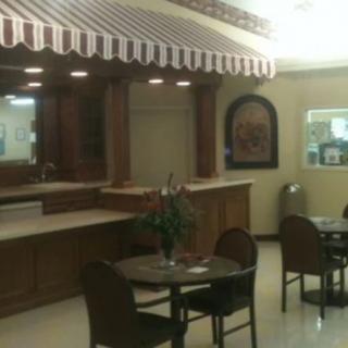 A small indoor cafe with tables and chairs, featuring a counter under a striped awning.