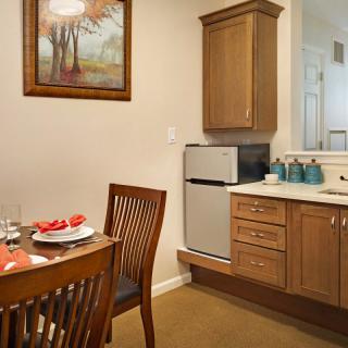 A cozy kitchen and dining area with wooden furniture and a mini fridge.