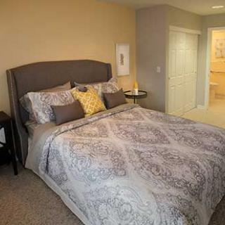 A cozy bedroom with a neatly made bed and decorative pillows.