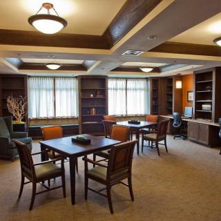 A cozy library room with tables, chairs, and bookshelves under soft lighting.