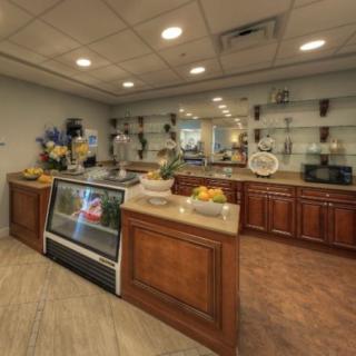A cozy bakery with a display case of pastries and decorative flowers on the counter.
