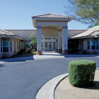 A building entrance with a landscaped driveway and neatly trimmed bushes.