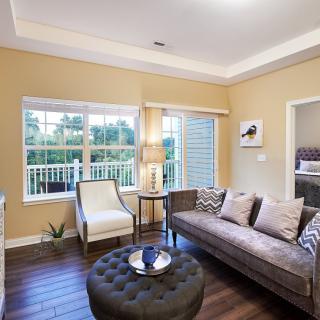 A cozy living room with a sofa, armchair, and coffee table placed on hardwood floors.