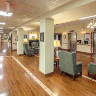 A spacious and well-lit lobby or waiting area with comfortable seating and wooden flooring.