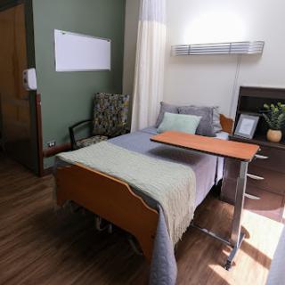 A well-designed hospital room featuring a bed, bedside table, and comfortable seating.