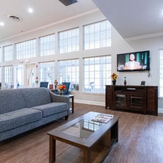 A modern living room with large windows, hardwood flooring, and a comfortable seating area.