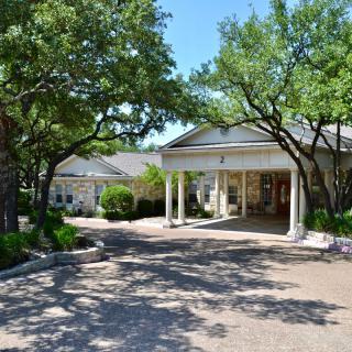 A residential house with a driveway surrounded by trees.