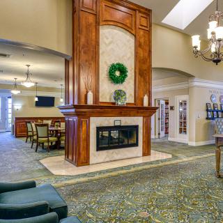 A spacious lobby featuring a central fireplace, elegant chandelier, and comfortable seating area.