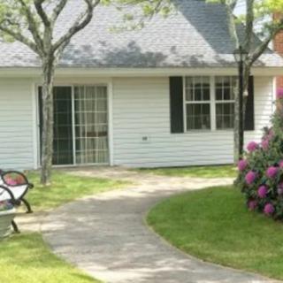 A cozy house with a winding pathway, surrounded by greenery and flowers.