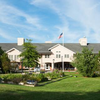 A welcoming residential building surrounded by lush greenery and a clear blue sky.