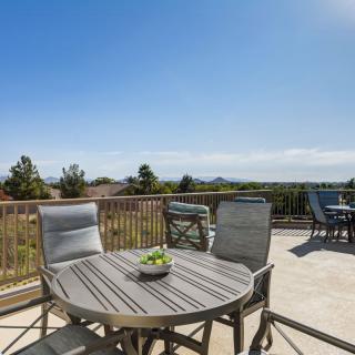 A sunny patio with outdoor furniture and a scenic view.