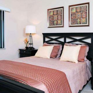 A cozy and well-decorated bedroom featuring a bed with patterned pillows and framed artwork on the wall.