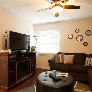 A cozy living room with a sofa, television, and decorative wall clocks.