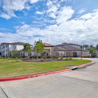 A suburban residential area with modern buildings, landscaped gardens, and a cloudy sky overhead.