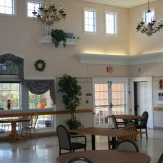 Bright and spacious lobby area with tables, chairs, and decorative plants.