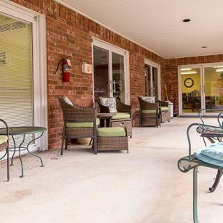 A cozy patio with comfortable outdoor seating and tables against a brick wall.