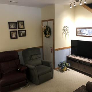 A cozy living room with recliner chairs, a TV, and decorative wall art.